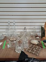 Photo of assorted crystal decanters, glass bottles, silver plate pot and other glassware