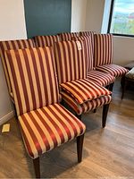 Front view of multiple striped upholstered dining chairs arranged in a row with pillow placed on one seat.