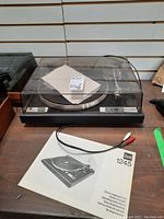 Front view of Dual CS 5000 turntable with dust cover closed, paperwork and RCA cable in front