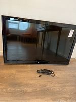 Front view of LG 42LS3400 TV with remote laid in front, showing screen and surrounding bezel.