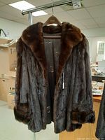 Full view of the mahogany mink fur jacket hanging showing front, collar, and pockets.