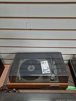 Front view of Panasonic turntable with wooden base and scratched plastic dust cover with auction tag visible