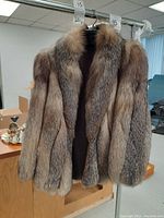 Front view of silver fox fur jacket hung on metal rack