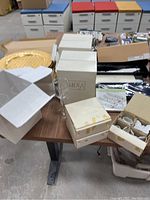 Photo showing assorted tableware items including boxed Mikasa wine glasses and gold-toned charger plates.