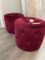 Photo of two matching velvet tufted poufs, showcasing their shape and color