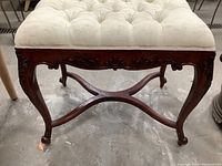 Side and front views of vintage mahogany tufted brocade top bench showing carved feet, detailed legs, curved stretcher beneath seat, and cream brocade fabric with floral pattern and button tufting.