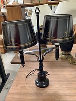 Black metal double-shade table lamp with gold decorative paint on shades.