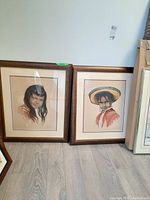 Two framed watercolour prints of children side by side against a wall.