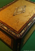 Close-up of the top corner showing birds eye maple wood grain, silver bands with circular button inlays and a central diamond-shaped mother of pearl and silver inlay.