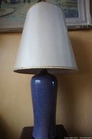 Front view of the purple glazed pottery lamp with original white shade and gold trim.