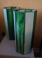Pair of green and white hexagonal tall slag glass lamp shades photographed together showing their size and color.