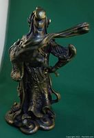 Side view of the statue highlighting the flowing ornamental ribbons and extended arm.