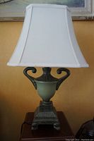 Full lamp with white fabric shade and urn shaped base with scroll handles and square clawed foot base.