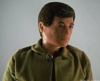 Close-up of G.I. Joe doll's face showing fuzzy felt style brown hair, blue eyes, and scar on cheek.