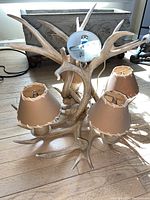 Antler chandelier with five attached brown fabric lampshades, natural rustic style, placed on wooden floor