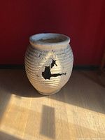 Front view of the off-white Grecian style replica pot showing the large cracked hole on its side.