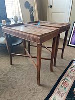 Two wooden side tables placed side-by-side, showing the legs, raised edges of the tops, and overall structure.