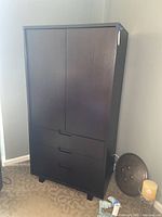 Full front view of tall dark wood cabinet with doors and drawers