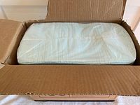 Open cardboard box showing neatly stacked white puppy training pads wrapped in clear plastic.