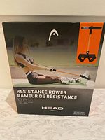 Front view of the boxed Head Fitness resistance rower showing product branding, image of the rower and a woman using it in the photo.