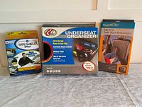 Photo showing the three boxed items in the lot: a windshield wrap, G&O underseat organizer, and High Road seat back protectors.