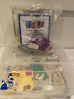 Clear container with loose Lego pieces and visible pack of 12 new stackable 6x6 Lego plates.