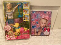 Front view of boxed Barbie Walk & Potty Pup set next to boxed Jojo Siwa Bow Kit
