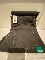 Folded men's Calvin Klein jeans showing rear pocket and waistband with attached size tag 38x30