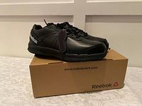 Side view of new black Reebok steel toe shoes on original box