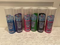 Six containers of Playfoam Pluffle in assorted colors arranged side by side on a table.