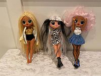 Three dolls standing side by side showing full outfits and hairstyles