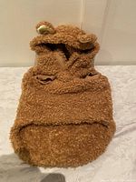 Front view of a brown teddy fleece dog jacket showing hood with ears and armholes.