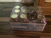 Box of 8 clear glass Anchor Hocking quart canning jars with metal lids, mostly unused appearance.