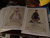Photo of two American Girls Collection children's paperback books titled Kirsten's Surprise and Meet Molly with illustrated covers.