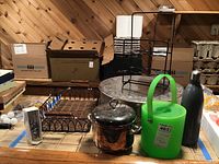 Photo showing metal and plastic ice buckets, metal tray, wire wine rack, cake stand, reusable bottle, and boxed decorative item on basement floor.