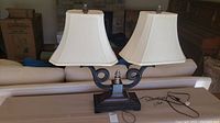 Front view of the Uttermost double lamp showing two white fabric shades and dark metal and wood base