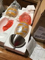 Unassembled pendant lights with glass swirled shades and metal fixtures packed in styrofoam.