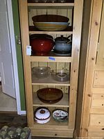Full view of shelf with all items: large pasta bowl, red lacquer jar, soup tureen, glass bowls, casserole, and plates.