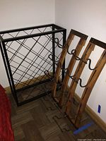 Photo showing two light wood wine racks with dark metal curved holders alongside one black metal lattice wine rack.