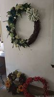 Full view of three different wreaths placed near a wall, showing their size and decoration styles