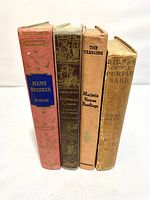 Front view of four vintage books in a row showing spines with titles and authors
