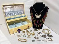 Photo of vintage and costume jewelry items displayed with vintage jewelry box and black necklace display.