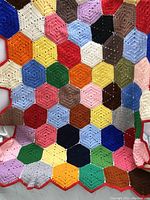 Close-up photo showing the colorful hexagonal crochet pattern and scalloped edge of the afghan throw.