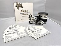 Full view of the candy memorabilia set including the book, the motorcycle model with a rider, and 12 recipe cards spread out in front
