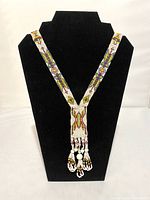 Necklace displayed on black bust showing front beadwork and tassels