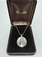 Front view of sterling silver round pendant with Aquarius zodiac engraving on a silver chain inside a velvet jewel box.
