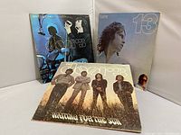 Photo of 3 Doors vinyl albums standing upright: Absolutely Live! with blue stage photo on cover, 13 with Jim Morrison portrait on front, and Waiting for the Sun with band portrait in field.