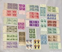 Top side view of all 24 blocks of U.S. stamps arranged on light surface, showing front of stamps with various colors and designs.