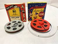 Two 8mm film reels with their original boxes, featuring Walt Disney and Charlie Chaplin films.