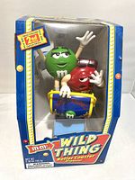 Front view of 2002 M&M Wild Thing Roller Coaster Dispenser in sealed original box showing green and red M&M characters and colorful graphics.